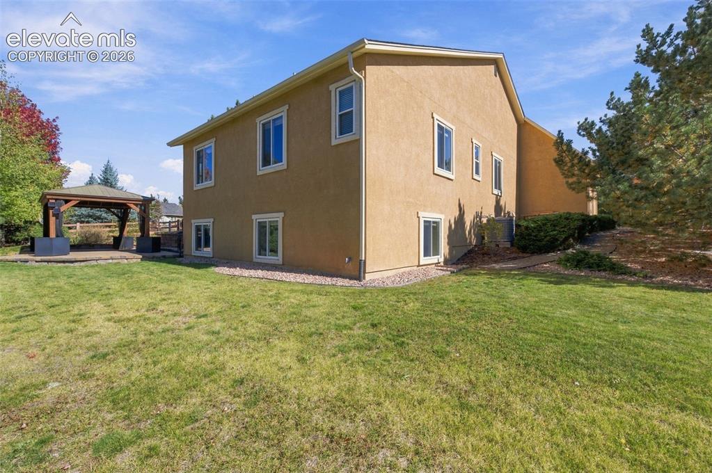 Image 41 of 48: Stucco exterior residence featuring an expansive lawn, detached timber-fram