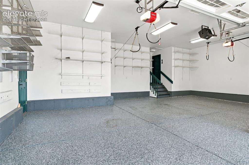 Image 45 of 48: Multi-car garage featuring epoxy-coated flooring, comprehensive wall-mounte