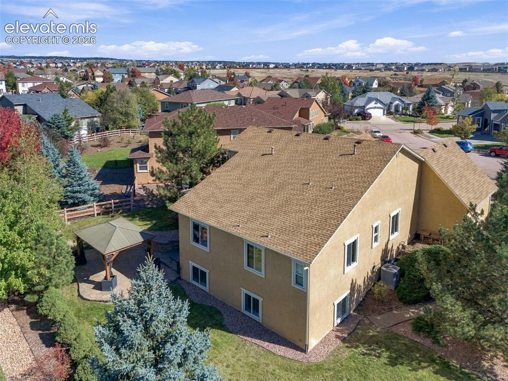 Image 46 of 48: Stucco exterior featuring an asphalt shingle roof, paved patio area with a 