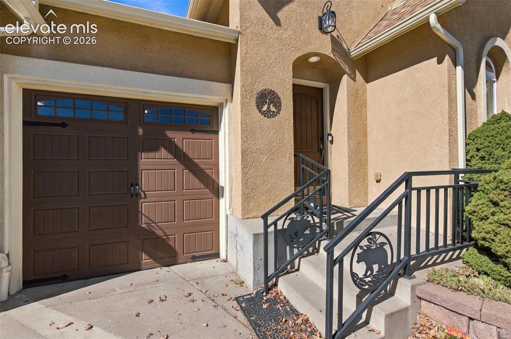 Image 5 of 48: Stucco exterior featuring a brown garage door with window panes, a recessed