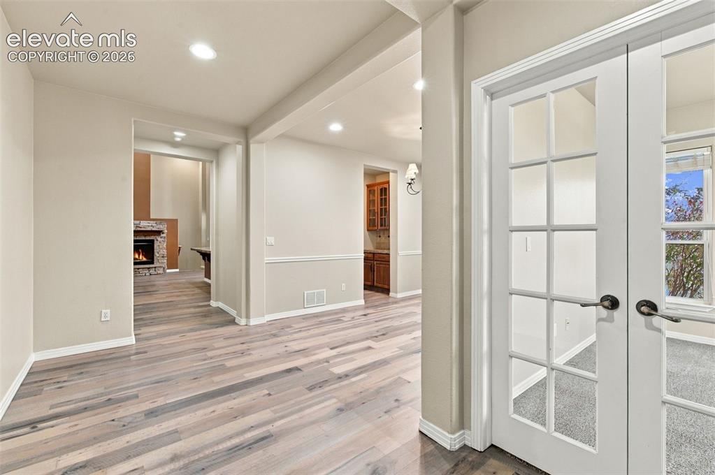Image 6 of 48: Wood-finish flooring, glass-paneled double doors, recessed lighting, chair