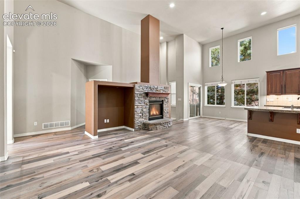 Image 7 of 48: Expansive double-height living area featuring wood-finish flooring, a centr