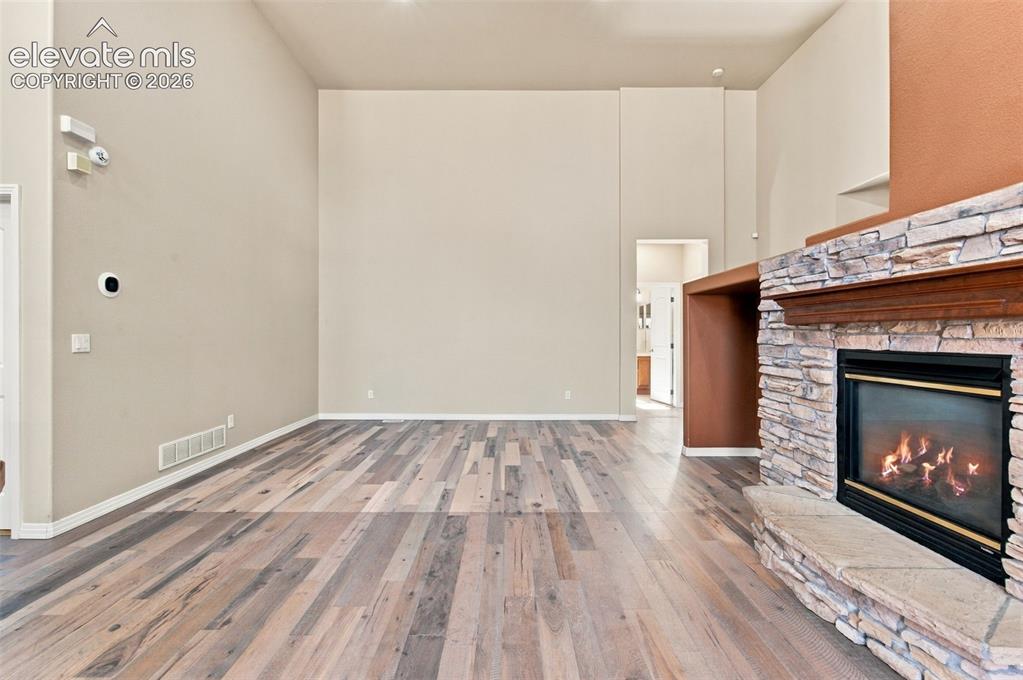 Image 8 of 48: High-ceilinged interior featuring wood-finish flooring and a stone-clad fir