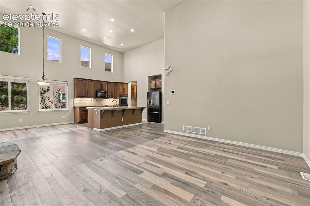 Image 9 of 48: High-ceiling interior space featuring wood-finish flooring, recessed lighti