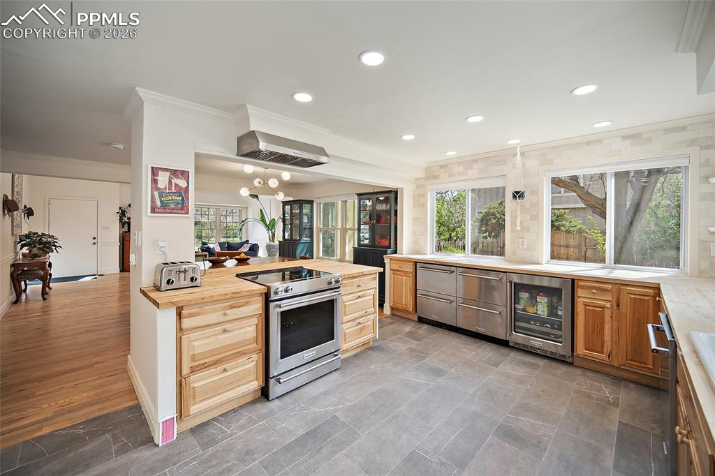 Image 15 of 50: Stone flooring in the kitchen. Wall of windows bring outdoors in. Under cab