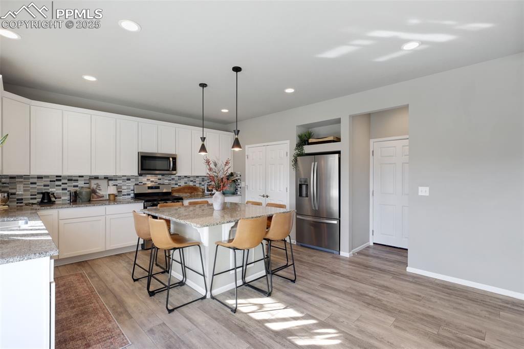 Image 12 of 39: Kitchen featuring hanging light fixtures, a kitchen breakfast bar, stainles