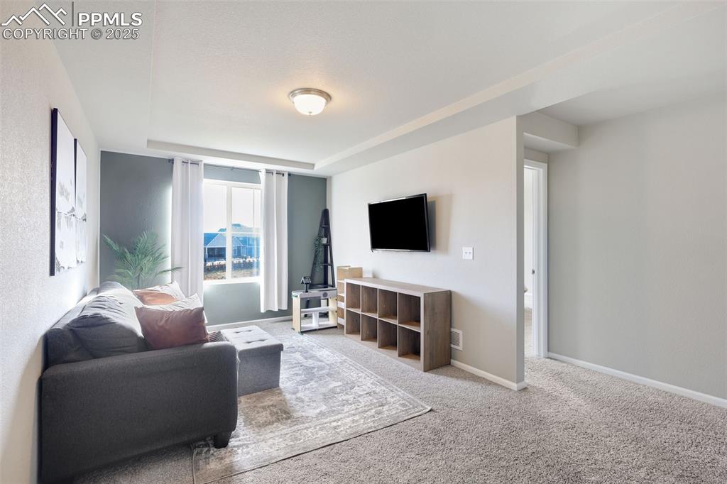 Image 14 of 39: Living area with light colored carpet and baseboards