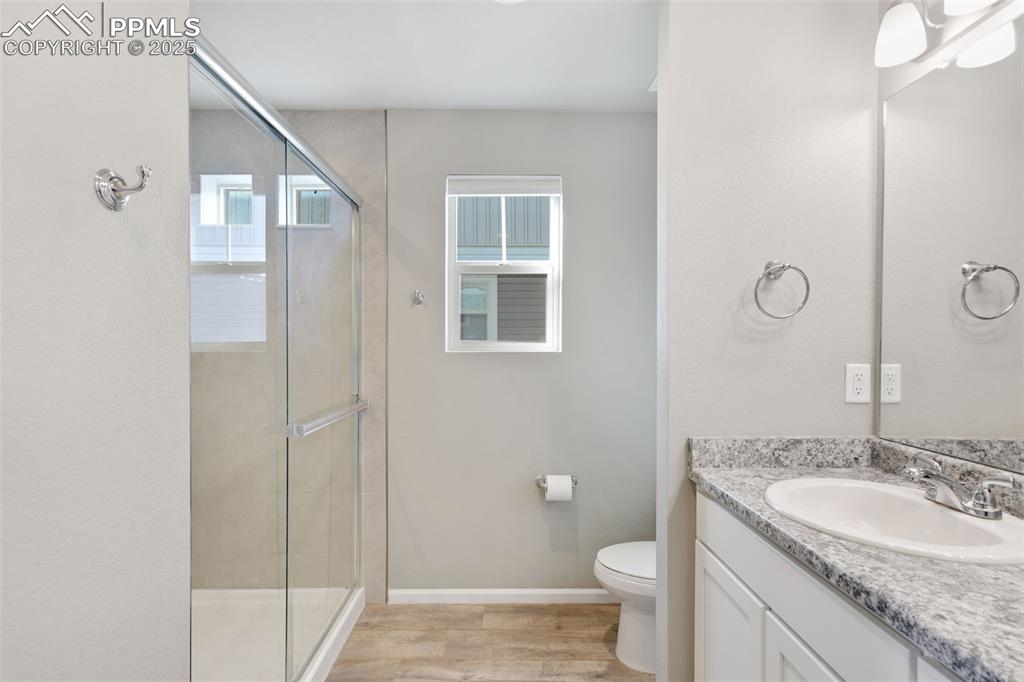 Image 20 of 39: Full bath with vanity, a shower stall, and light wood-style flooring