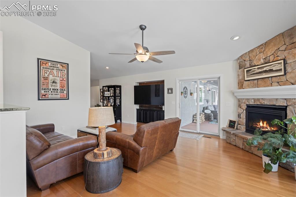 Image 10 of 49: Living room featuring ceiling fan, light wood finished floors, a fireplace,