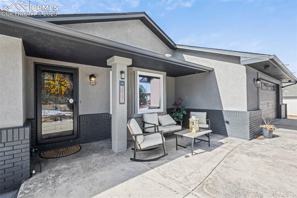 Image 2 of 49: Entrance to property with a garage, stucco siding, and brick siding