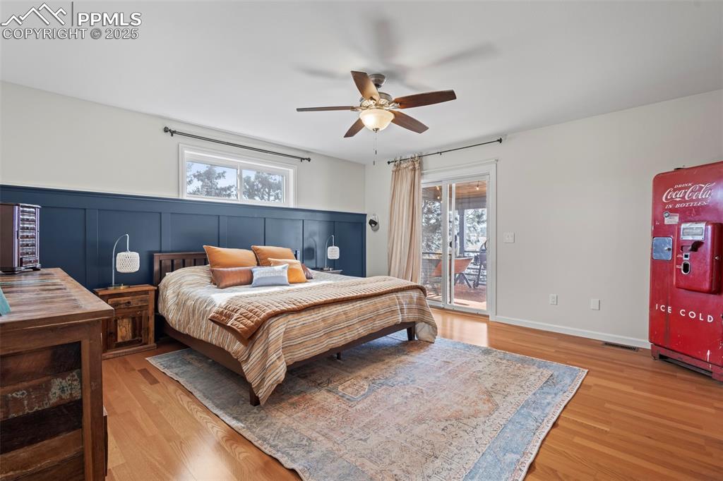 Image 20 of 49: Bedroom with multiple windows, wood finished floors, and access to exterior
