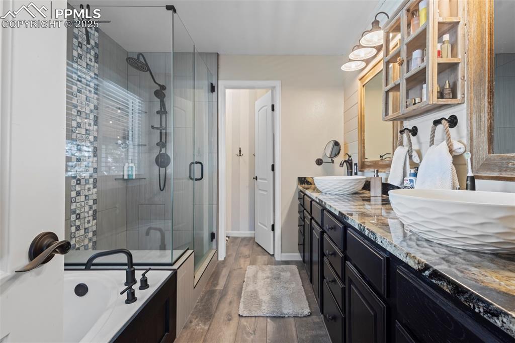Image 22 of 49: Full bathroom featuring double vanity, a stall shower, a sink, and wood fin