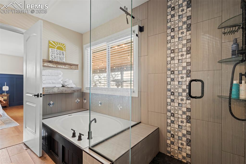Image 23 of 49: Bathroom with wood finished floors, tiled shower, a garden tub, and connect