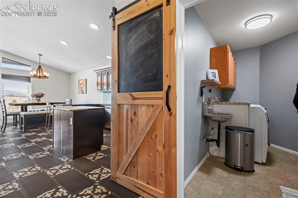 Image 25 of 49: Kitchen with a barn door, a kitchen island, baseboards, washer / clothes dr