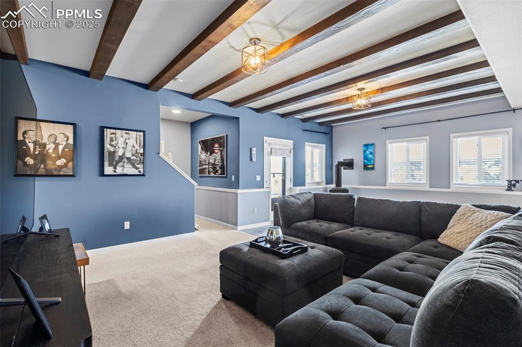 Image 32 of 49: Living area featuring beamed ceiling, carpet flooring, and baseboards