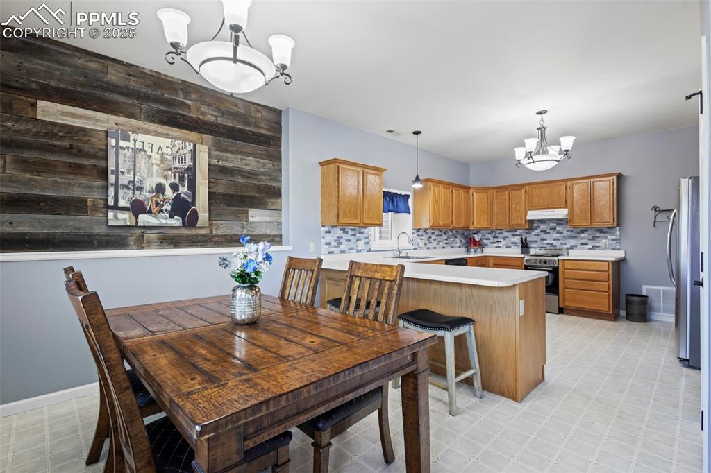 Image 35 of 49: Dining area featuring light floors, wooden walls, baseboards, and a notable