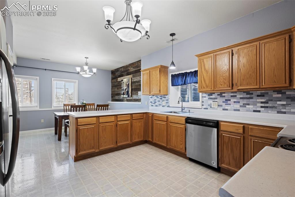 Image 36 of 49: Kitchen with hanging light fixtures, a notable chandelier, light countertop