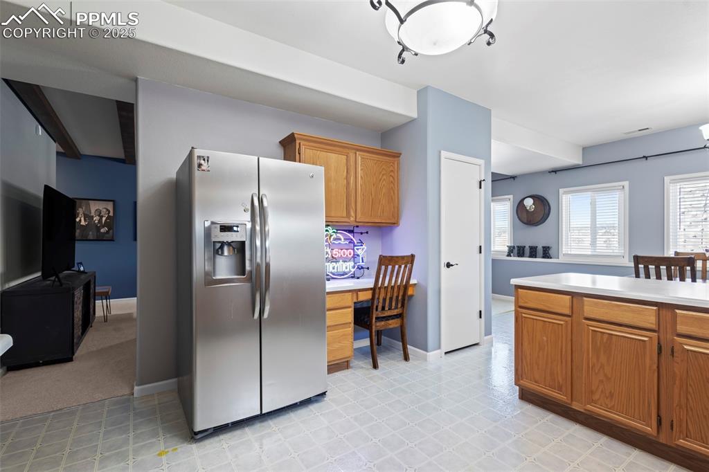 Image 37 of 49: Kitchen featuring brown cabinets, stainless steel fridge with ice dispenser