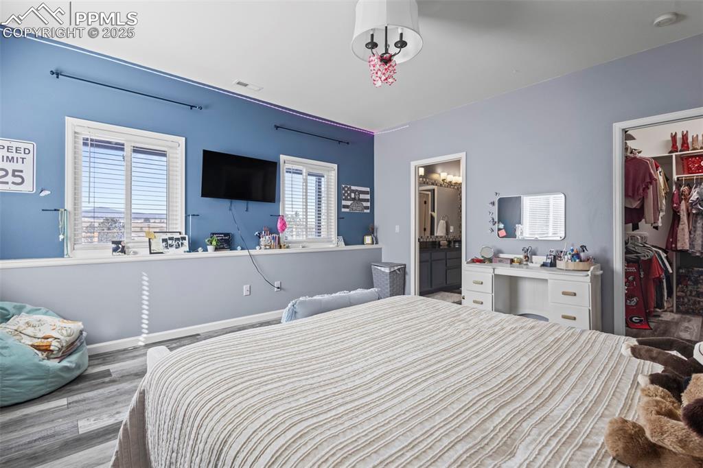 Image 40 of 49: Bedroom featuring a walk in closet, a closet, visible vents, light wood-sty