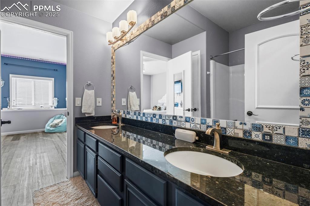 Image 41 of 49: Full bath with double vanity, a sink, baseboards, and wood finished floors