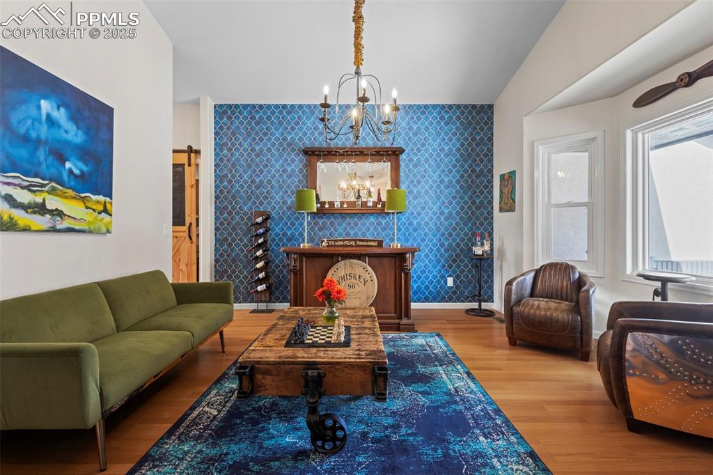 Image 5 of 49: Living area with an accent wall, a barn door, and wallpapered walls