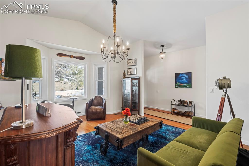 Image 6 of 49: Living area with lofted ceiling, baseboards, and wood finished floors