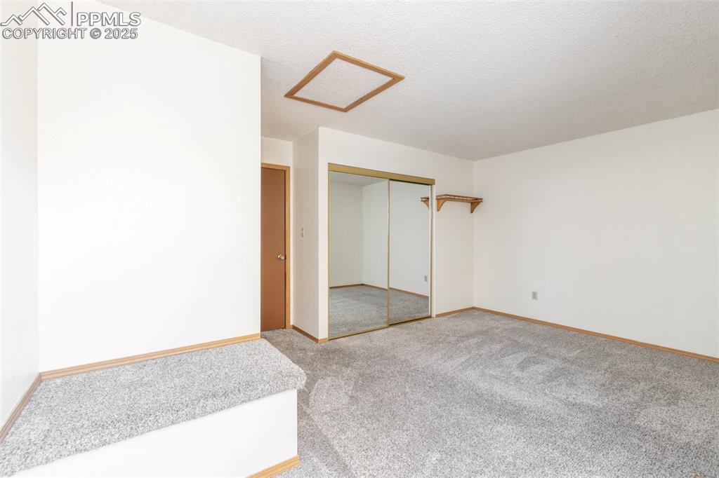 Image 14 of 31: Unfurnished bedroom featuring attic access, carpet, a textured ceiling, and
