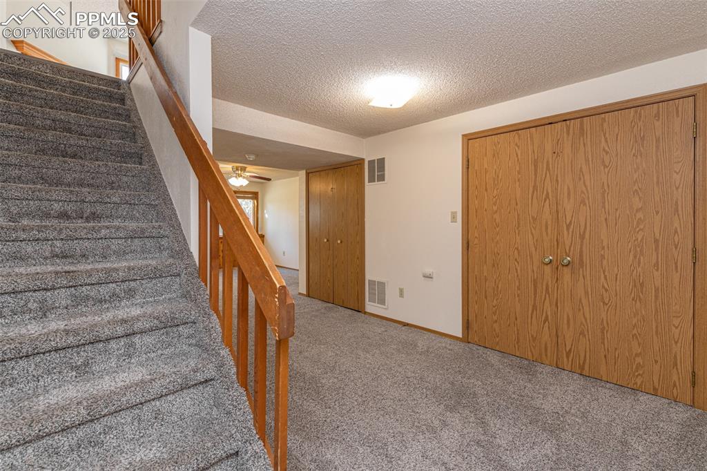 Image 18 of 31: Stairs with a textured ceiling, carpet, and ceiling fan