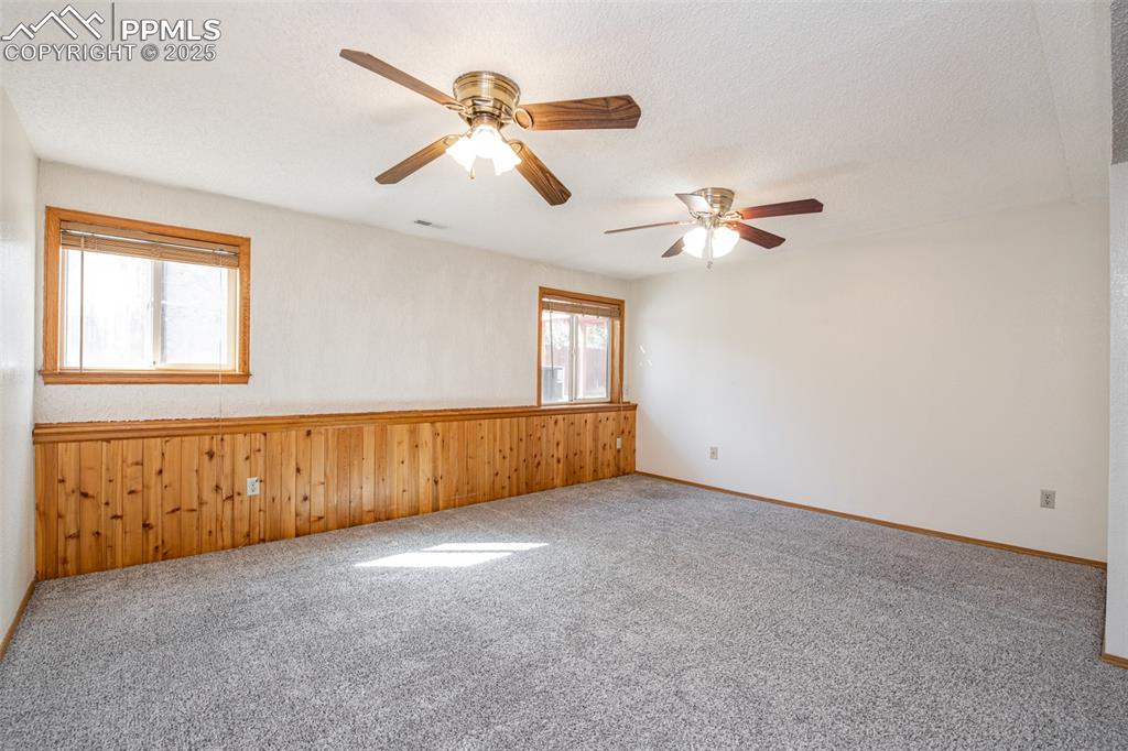 Image 20 of 31: Unfurnished room with carpet flooring, wood walls, a textured ceiling, and