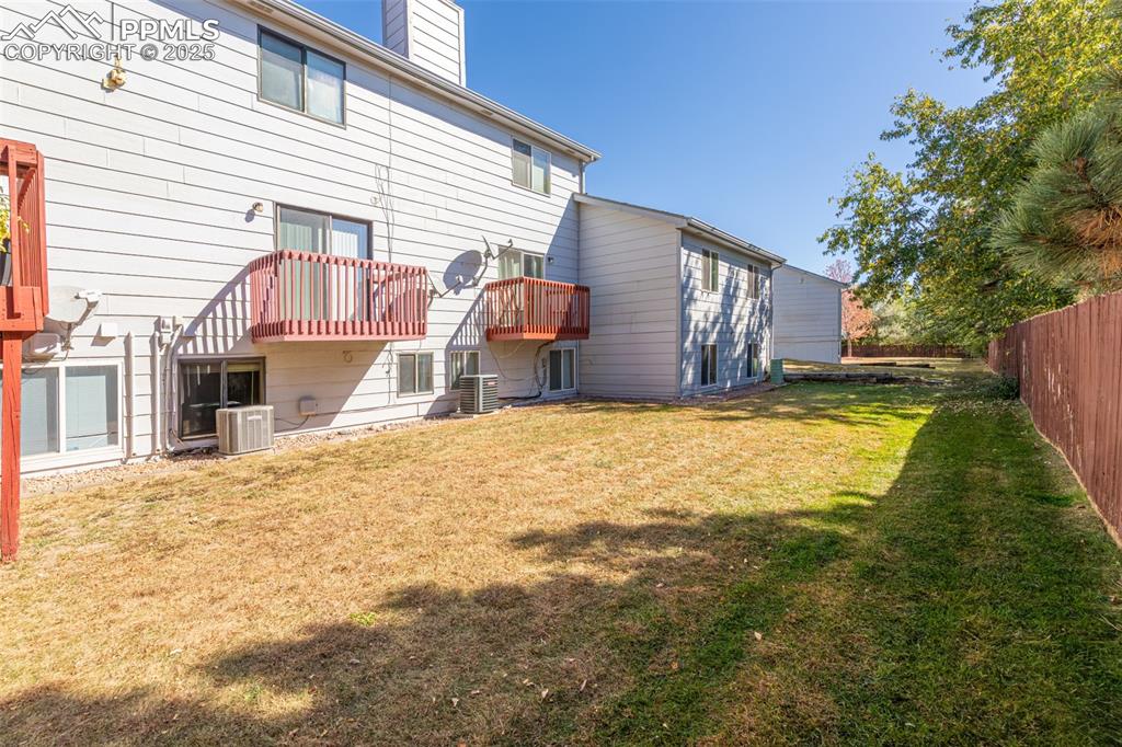 Image 28 of 31: Rear view of house with a chimney, a yard, and a balcony