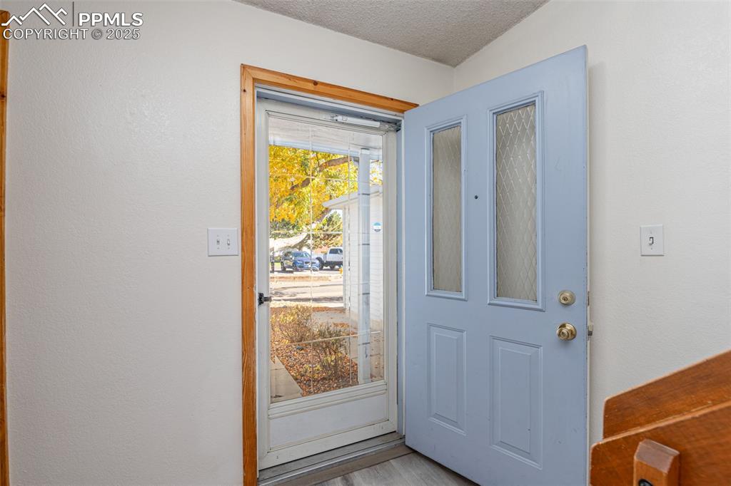 Image 4 of 31: Doorway to outside featuring a textured wall, a textured ceiling, and wood