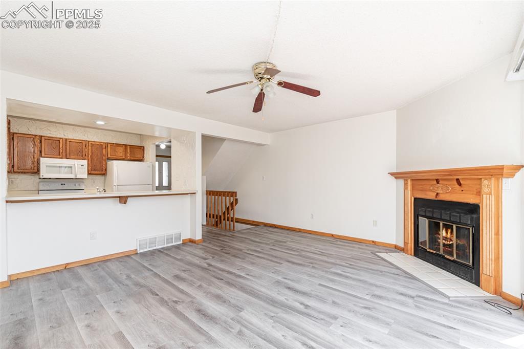 Image 7 of 31: Unfurnished living room with light wood-style flooring, a glass covered fir