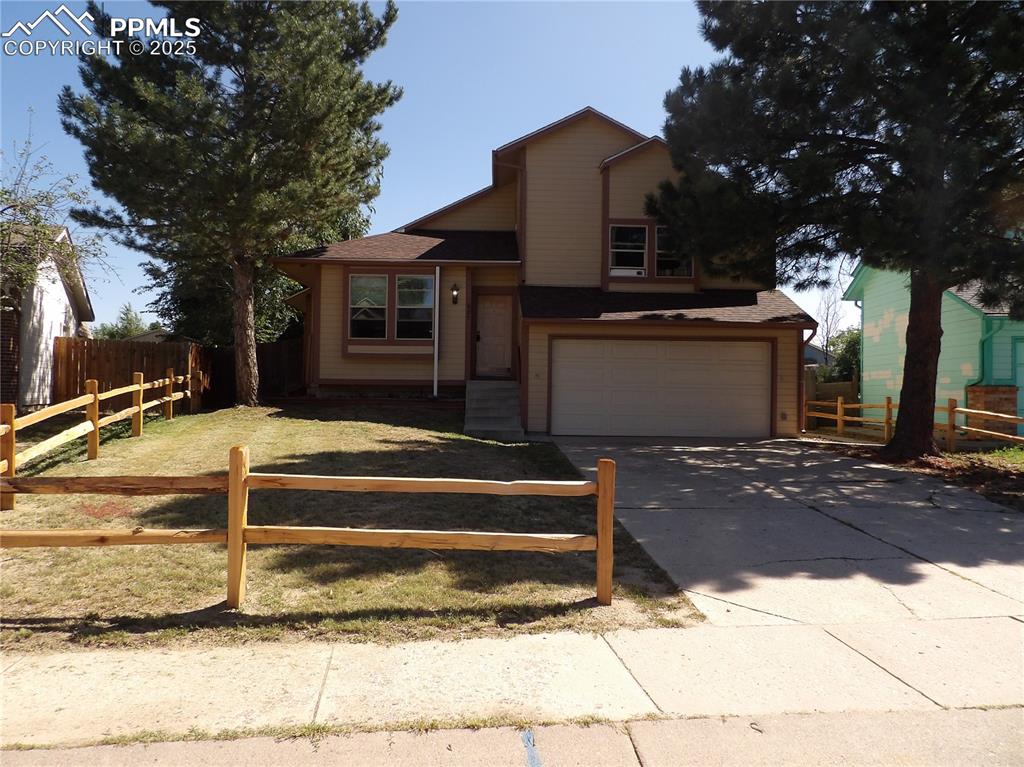 Caption: View of front of home featuring an attached garage, concrete driveway, and a shingled roof