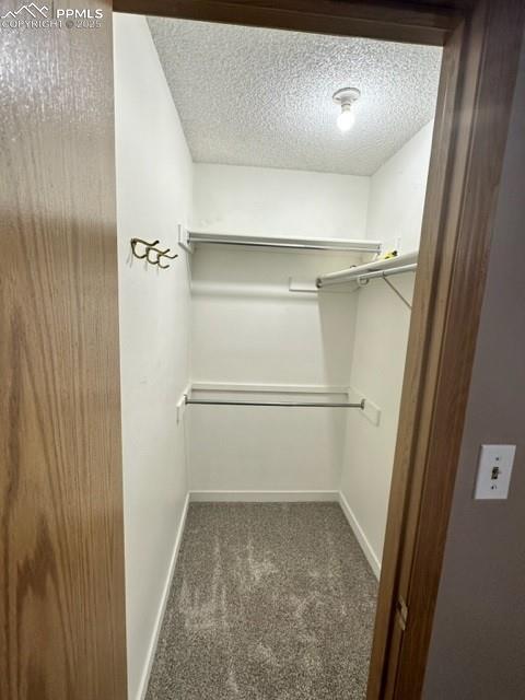 Image 21 of 24: Walk in closet featuring dark colored carpet