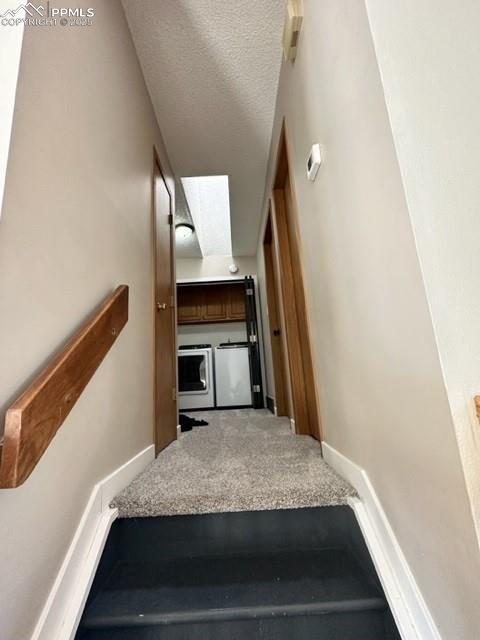 Image 24 of 24: Staircase featuring a textured ceiling, a skylight, carpet floors, and wash