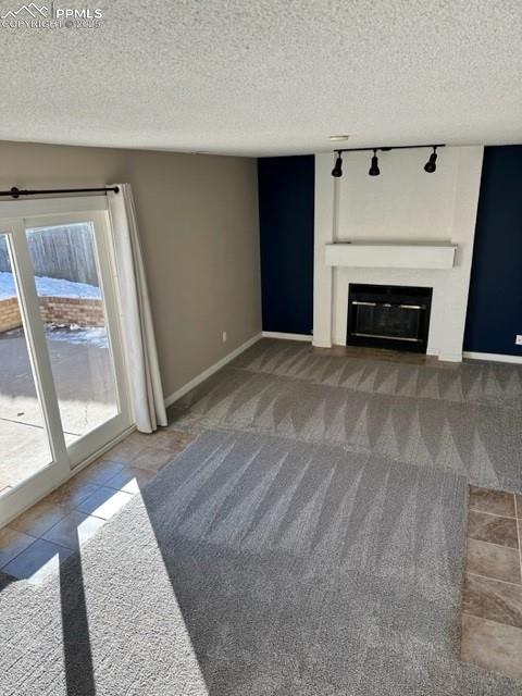 Image 7 of 24: Unfurnished living room with a glass covered fireplace, a textured ceiling,