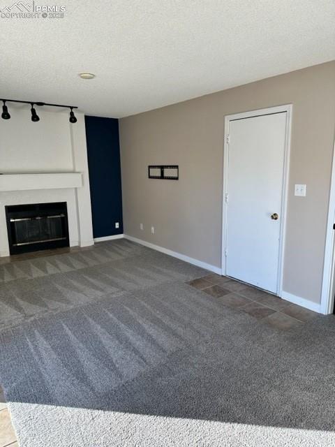 Image 8 of 24: Unfurnished living room featuring carpet flooring, a glass covered fireplac