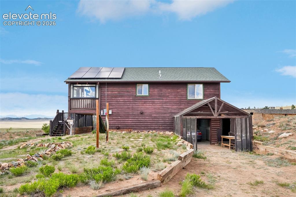 Image 12 of 33: Wood-sided property featuring a green-shingled roof and roof-mounted solar 