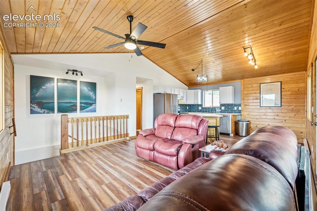 Image 16 of 33: Open-concept living area featuring wood-finish flooring and a sloped wood-p