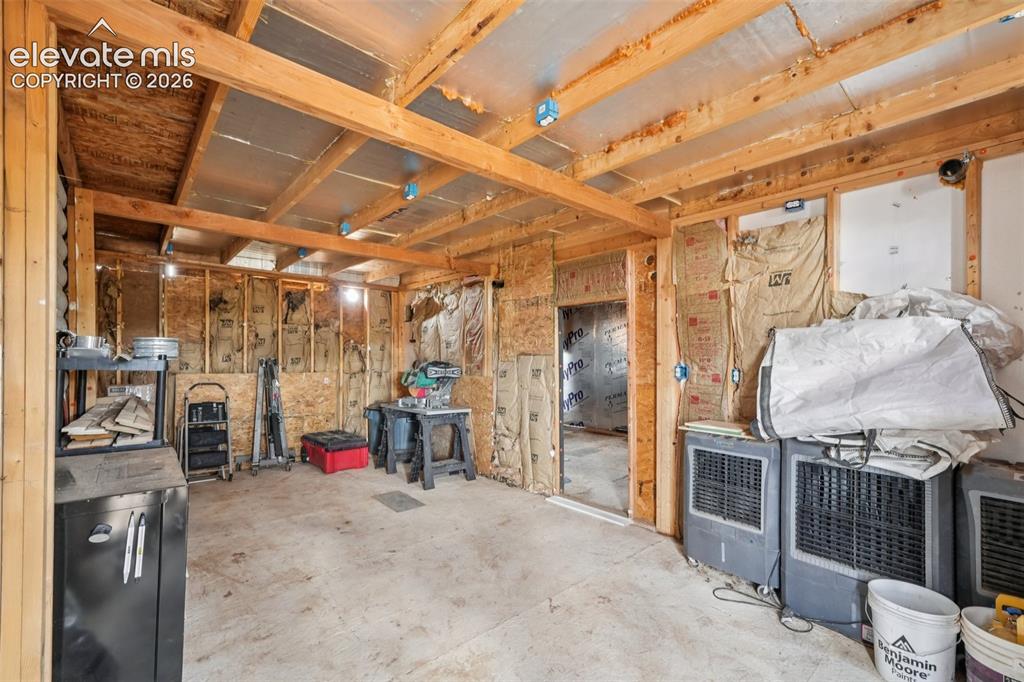 Image 20 of 33: Unfinished interior space with exposed wooden ceiling beams and wall studs