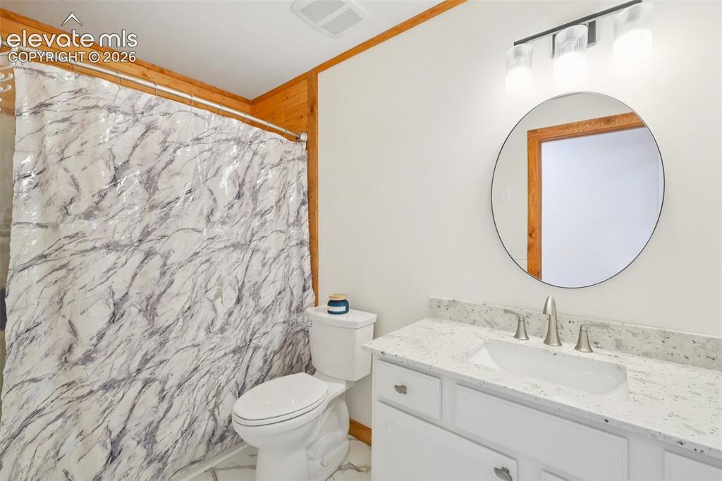 Image 21 of 33: Bathroom featuring a white vanity with an undermount sink, a light-toned sp