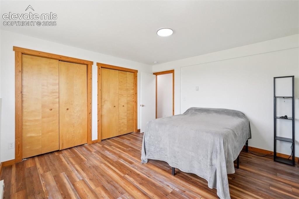 Image 22 of 33: Room featuring wood-finish flooring, two sets of bi-fold closet doors with 