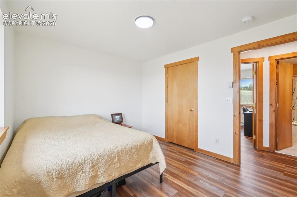 Image 25 of 33: Room featuring wood-finish flooring, white walls, and natural wood trim