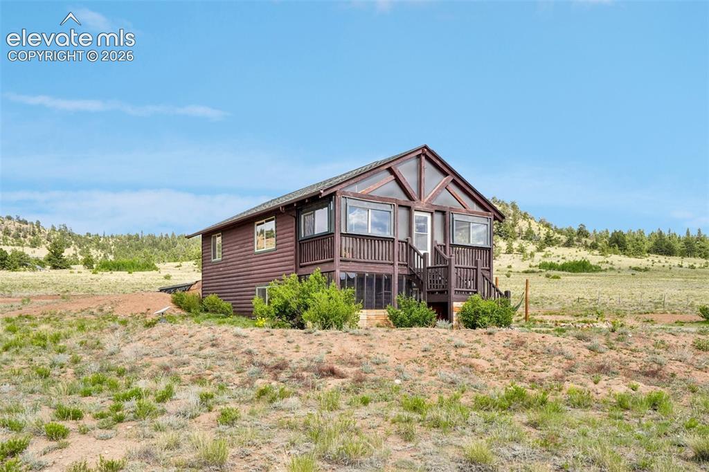 Image 3 of 33: Wood-sided cabin-style home featuring a covered front porch with railings, 