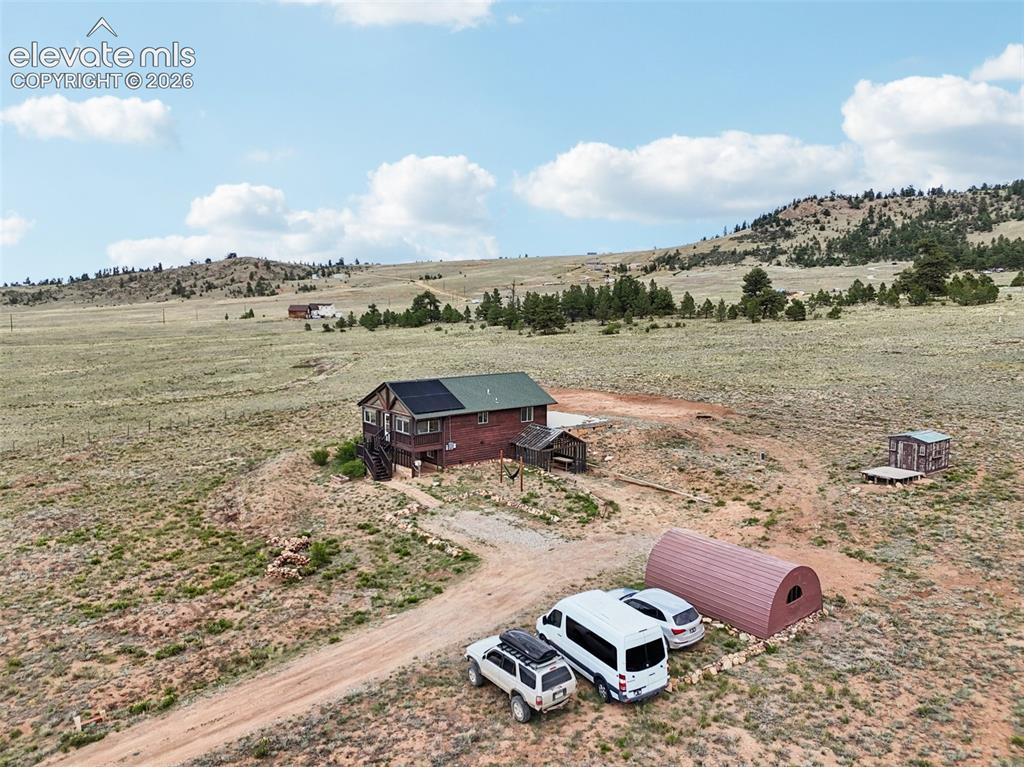Image 7 of 33: Rural property featuring a wood-sided residence with a green roof and visib