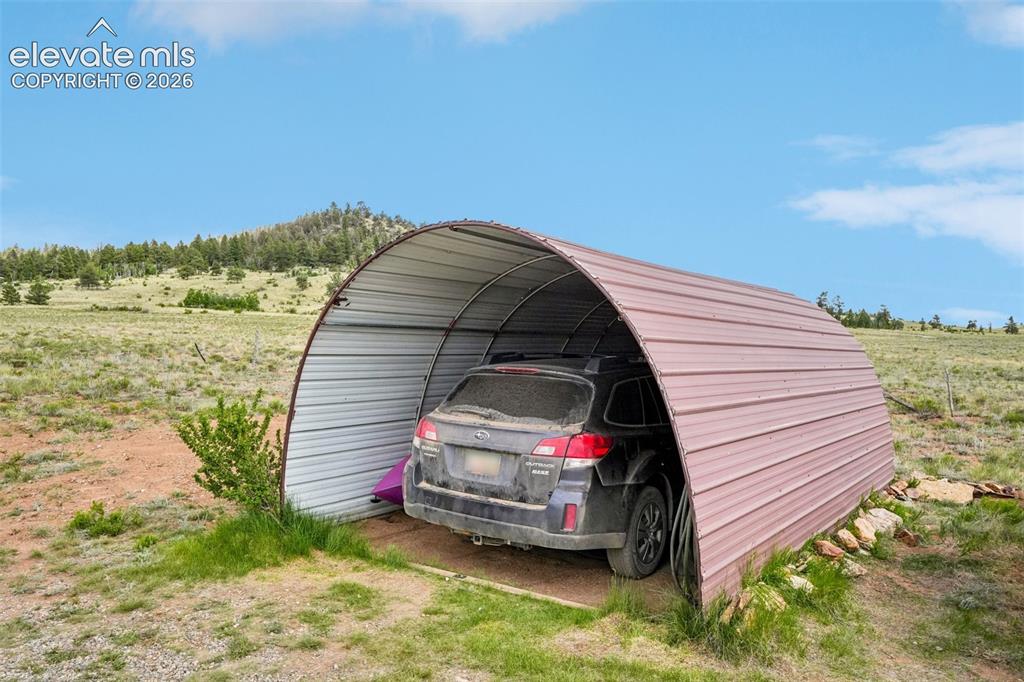 Image 8 of 33: Metal corrugated arch carport on a natural landscape