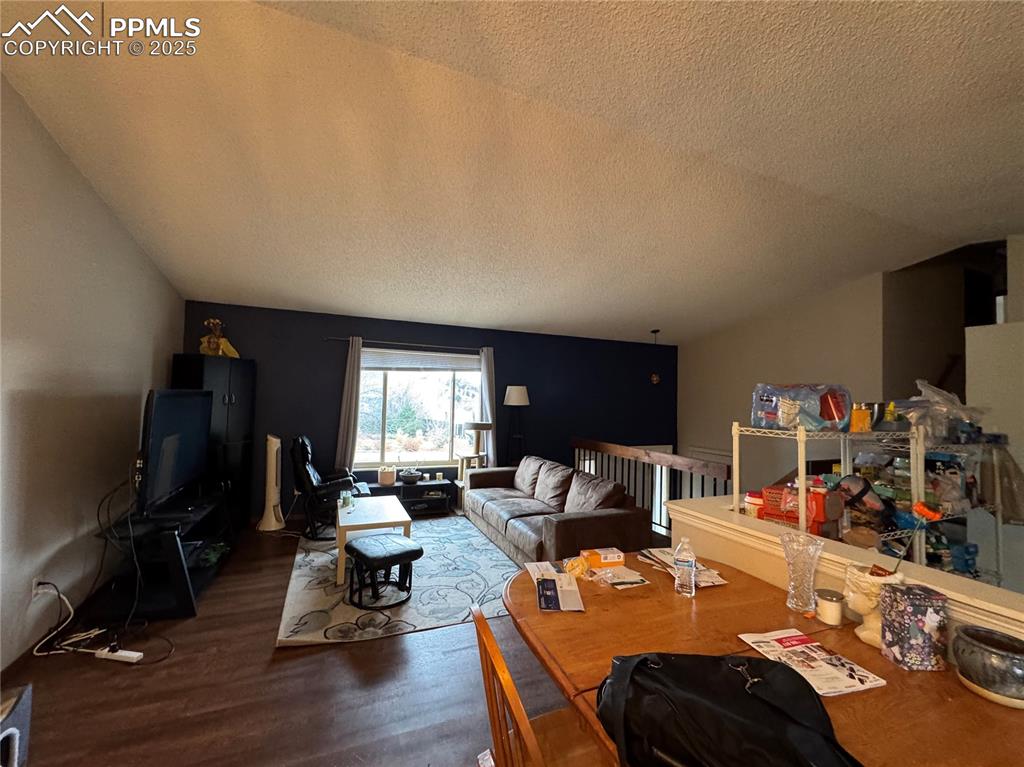 Image 6 of 8: Living area featuring a textured ceiling, wood finished floors, and lofted