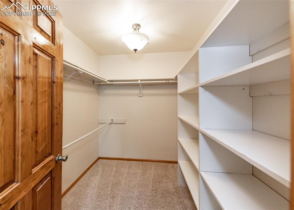 Image 32 of 50: Primary suite walk-in closet with ample shelving and hanging areas.