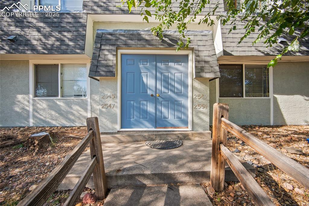 Caption: Property entrance with stucco siding and roof with shingles