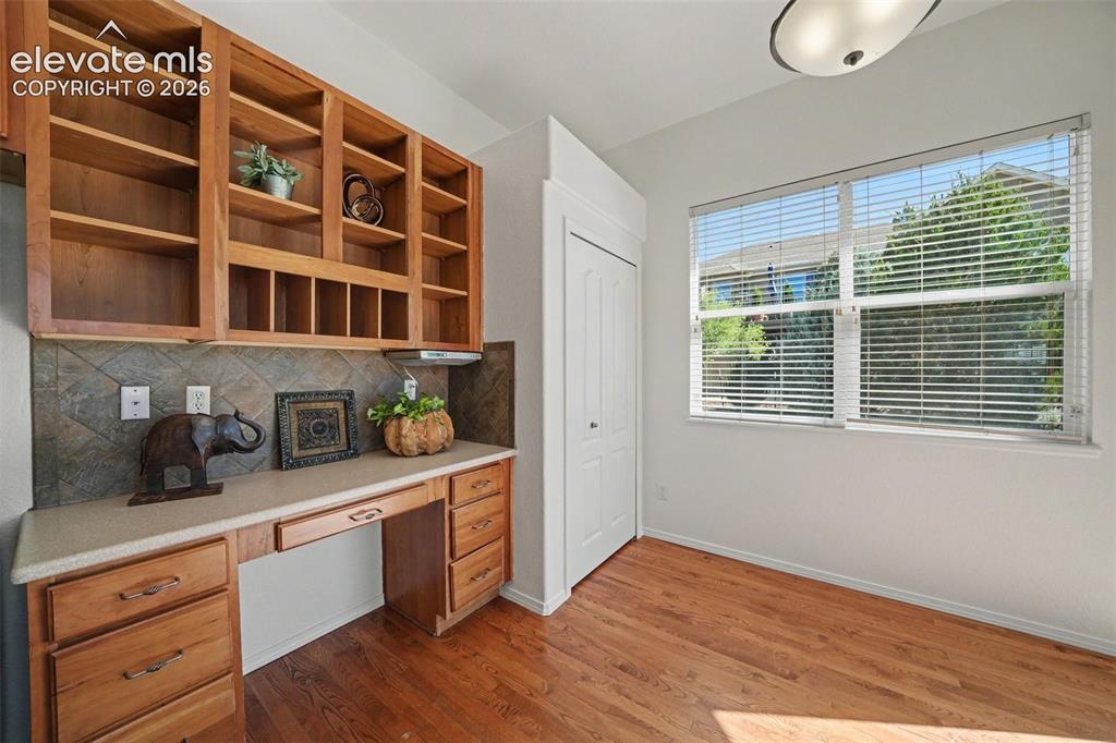 Image 12 of 41: Built-in desk area in the kitchen with pantry beside.